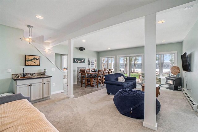 living room featuring a baseboard radiator, light carpet, a wood stove, and recessed lighting