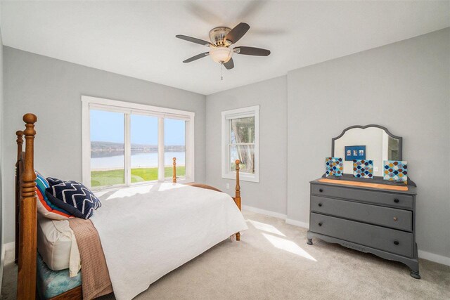 bedroom with baseboards, a water view, and light carpet