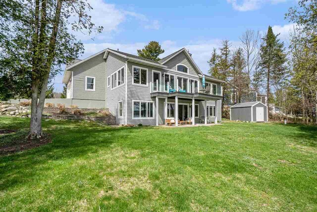 rear view of house featuring a lawn, a storage unit, an outdoor structure, and a patio