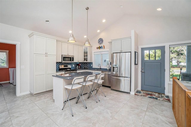 kitchen featuring dark countertops, a breakfast bar, a center island, tasteful backsplash, and appliances with stainless steel finishes