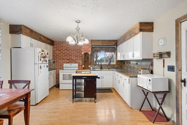 kitchen with a sink, a chandelier, light wood-style floors, white appliances, and white cabinetry