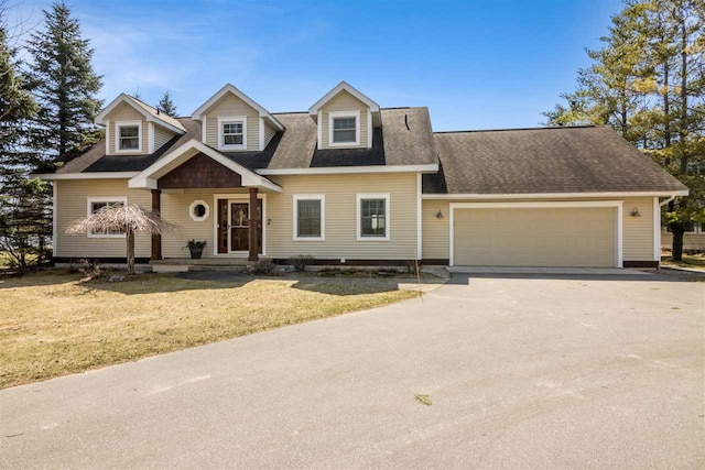 view of front of home featuring concrete driveway, a front lawn, roof with shingles, and a garage