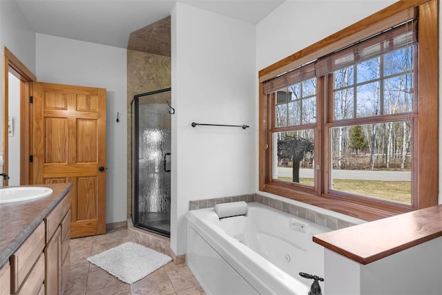 bathroom with a tub with jets, a stall shower, and vanity