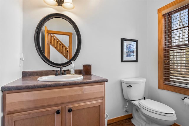 half bathroom with toilet, baseboards, and vanity