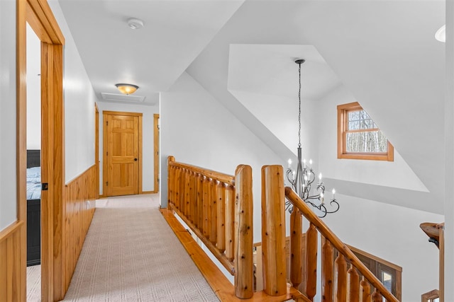 corridor featuring an inviting chandelier, visible vents, wood walls, a wainscoted wall, and vaulted ceiling
