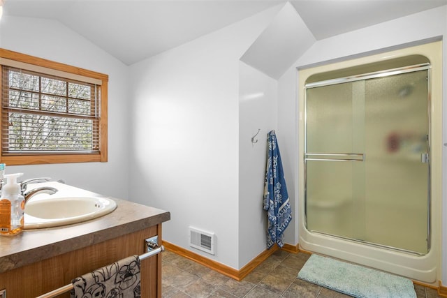 full bathroom featuring vanity, baseboards, a shower stall, vaulted ceiling, and visible vents