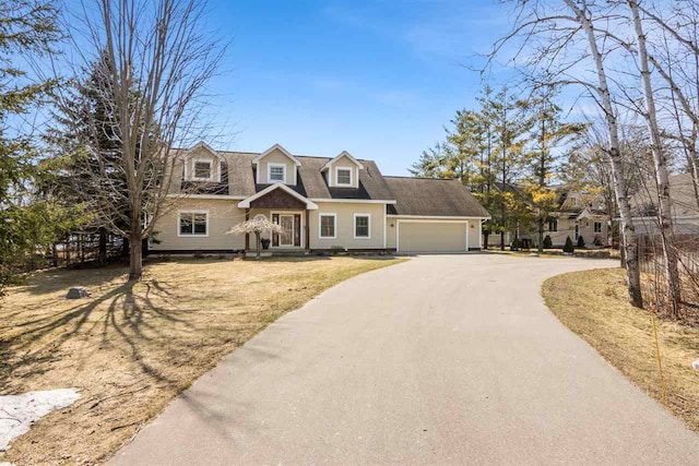 cape cod-style house featuring a garage, driveway, and a front lawn