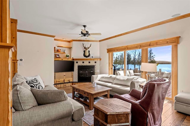 living room with crown molding, ceiling fan, hardwood / wood-style floors, and a tile fireplace