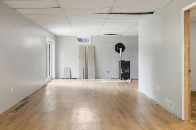 5748 Evergreen Trl, Petoskey, MI 49770 - below grade area with a wood stove, a drop ceiling, light wood-style flooring, and visible vents