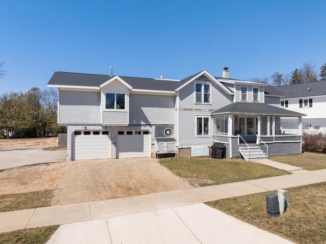 view of front of house featuring an attached garage, a porch, a front yard, a chimney, and driveway