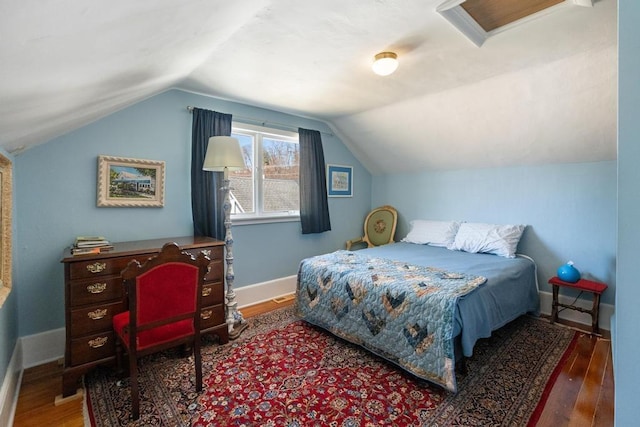 bedroom featuring baseboards, vaulted ceiling, and wood finished floors