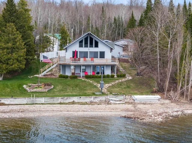 rear view of property with a lawn, stairs, a deck with water view, and a forest view