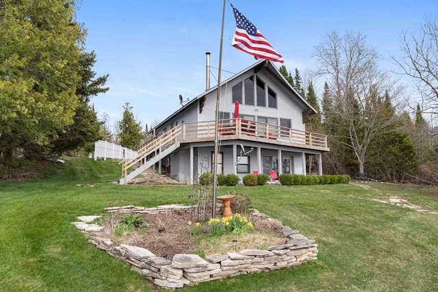 rear view of house with a yard, a wooden deck, and stairs