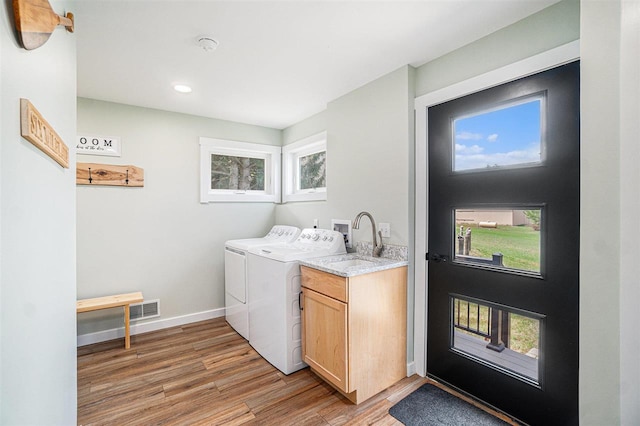 4852 Six Mile Lake Rd, Ellsworth, MI 49729 - clothes washing area with visible vents, cabinet space, separate washer and dryer, and light wood-type flooring