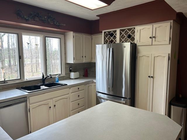 8118 E Mitchell St, Petoskey, MI 49770 - kitchen featuring a sink, backsplash, stainless steel appliances, and white cabinetry