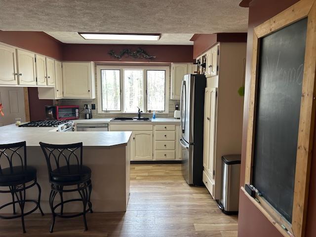 8118 E Mitchell St, Petoskey, MI 49770 - kitchen with a peninsula, light wood-style floors, light countertops, a sink, and appliances with stainless steel finishes