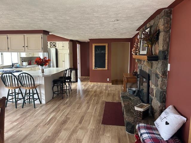 8118 E Mitchell St, Petoskey, MI 49770 - kitchen featuring freestanding refrigerator, a textured ceiling, light wood-type flooring, and a kitchen bar