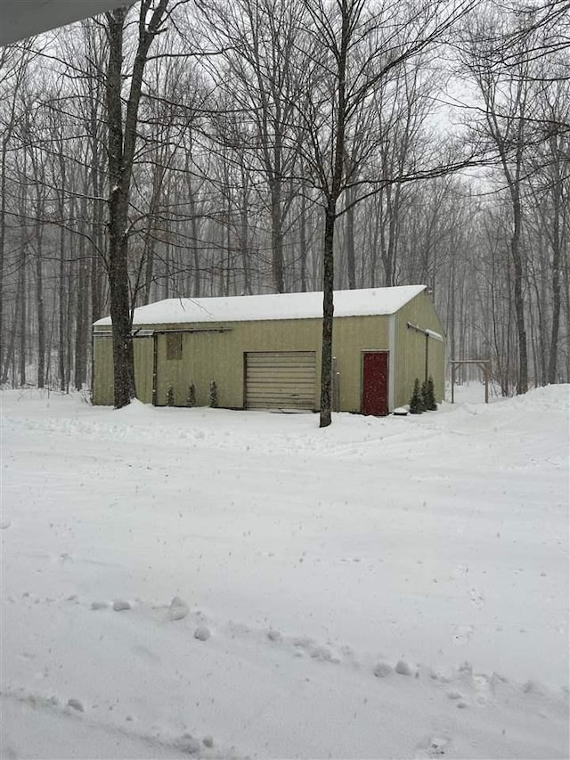 8118 E Mitchell St, Petoskey, MI 49770 - snow covered structure featuring a garage, an outdoor structure, and an outbuilding