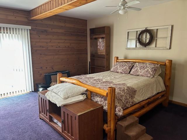 8118 E Mitchell St, Petoskey, MI 49770 - carpeted bedroom with wooden walls and a ceiling fan