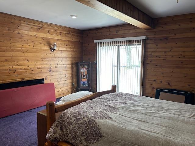 8118 E Mitchell St, Petoskey, MI 49770 - carpeted bedroom with wooden walls and a fireplace