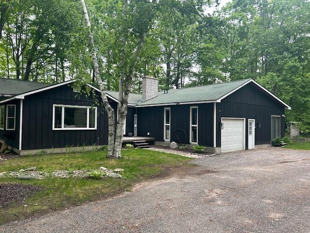 8118 E Mitchell St, Petoskey, MI 49770 - single story home with a chimney, board and batten siding, a garage, and driveway