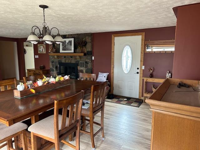 8118 E Mitchell St, Petoskey, MI 49770 - dining room with a textured ceiling, an inviting chandelier, a stone fireplace, and light wood finished floors