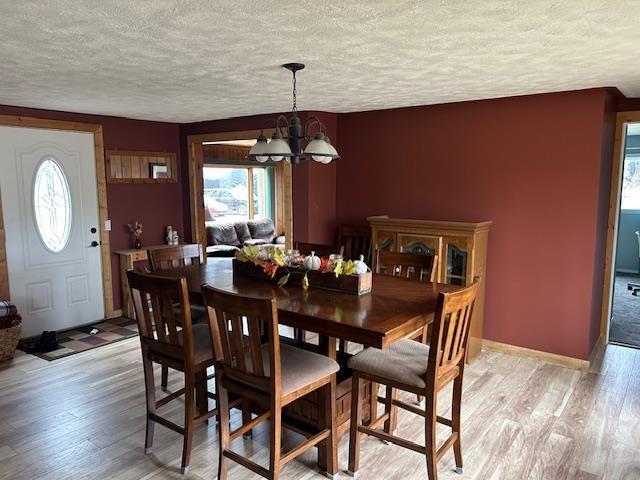 8118 E Mitchell St, Petoskey, MI 49770 - dining area with an inviting chandelier, light wood-style flooring, a textured ceiling, and baseboards