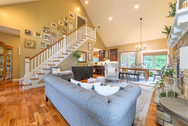 living room with stairs, high vaulted ceiling, baseboards, light wood-style flooring, and a notable chandelier