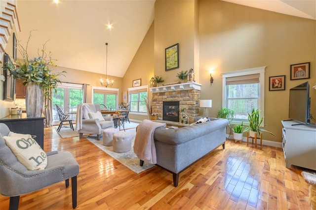 living room with a notable chandelier, light wood-style flooring, a healthy amount of sunlight, and high vaulted ceiling