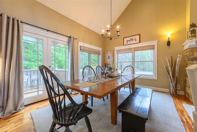 dining room with light wood finished floors, an inviting chandelier, baseboards, and high vaulted ceiling