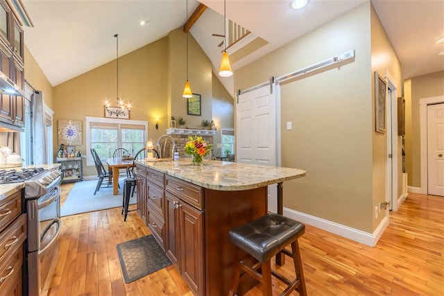 kitchen featuring a breakfast bar, double oven range, a barn door, and light wood-style floors