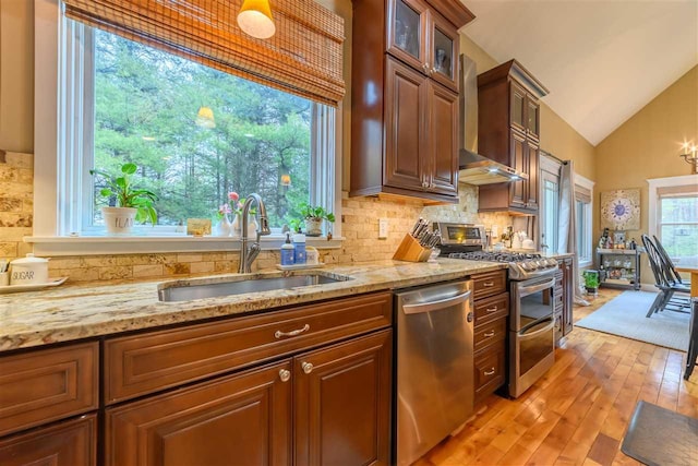 kitchen with decorative backsplash, appliances with stainless steel finishes, a sink, and vaulted ceiling