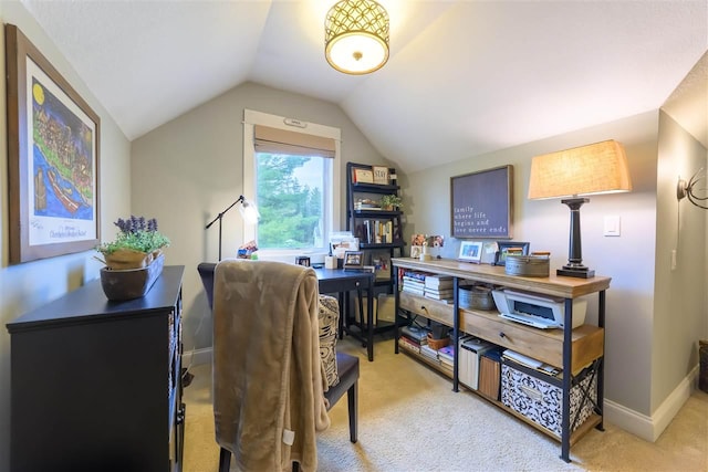 office area featuring light carpet, lofted ceiling, and baseboards