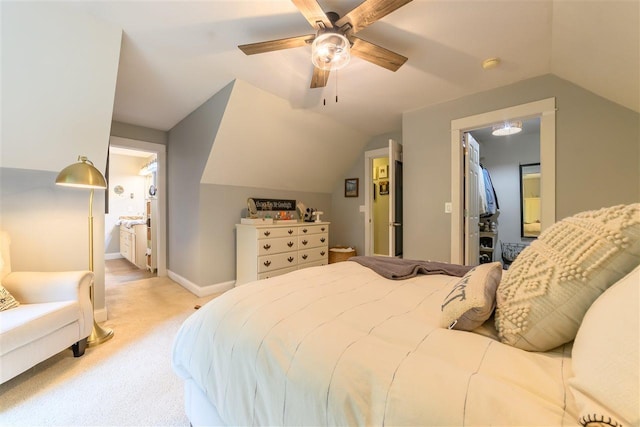 bedroom with ensuite bathroom, ceiling fan, light colored carpet, and vaulted ceiling