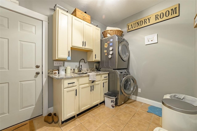 clothes washing area with light tile patterned floors, a sink, cabinet space, stacked washer and dryer, and baseboards