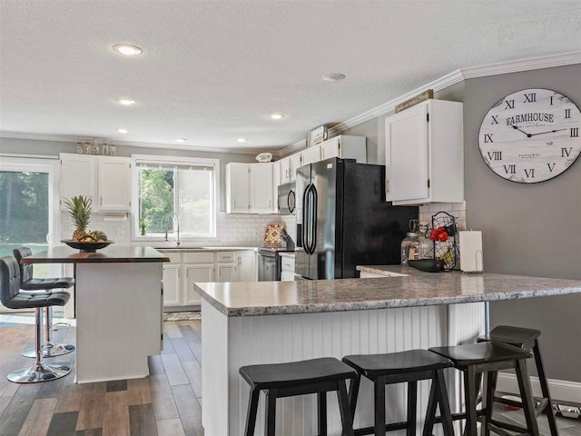 7906 Ferry Rd, East Jordan, MI 49727 - kitchen featuring black appliances, a peninsula, crown molding, and wood finished floors