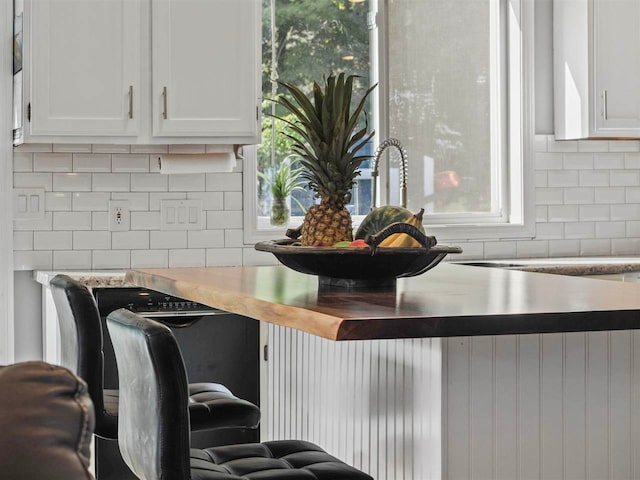 7906 Ferry Rd, East Jordan, MI 49727 - kitchen featuring light countertops, white cabinetry, decorative backsplash, and a healthy amount of sunlight