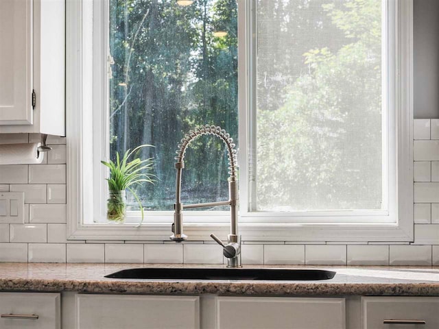 7906 Ferry Rd, East Jordan, MI 49727 - room details with a sink, light stone countertops, tasteful backsplash, and white cabinets