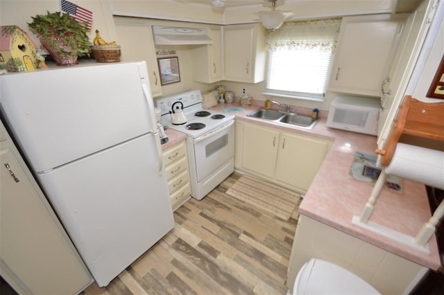 kitchen featuring light wood finished floors, white appliances, light countertops, and a sink