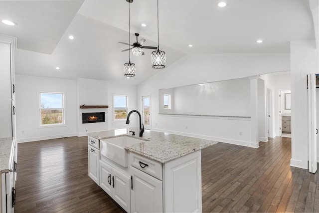 358 Harbor View Ln, Petoskey, MI 49770 - kitchen featuring a sink, open floor plan, white cabinetry, vaulted ceiling, and a warm lit fireplace