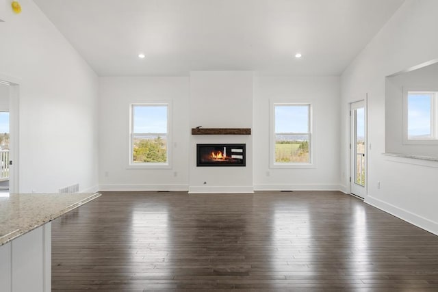 358 Harbor View Ln, Petoskey, MI 49770 - unfurnished living room featuring dark wood finished floors, plenty of natural light, visible vents, and a glass covered fireplace
