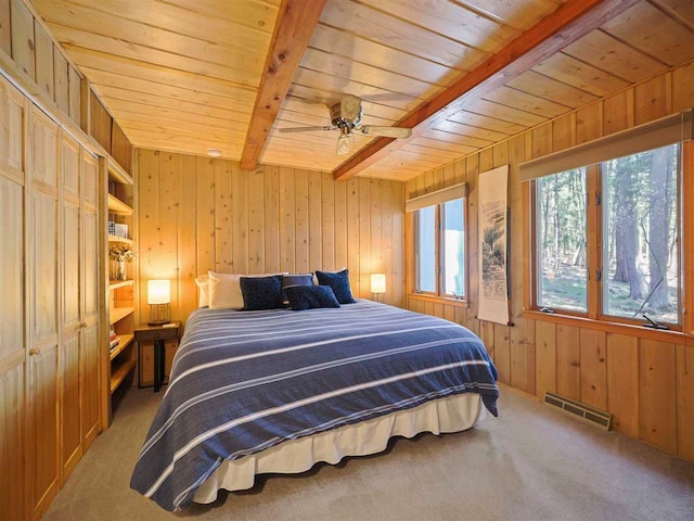 4488 Fourth St, Walloon Lake, MI 49796 - carpeted bedroom with a ceiling fan, visible vents, wood ceiling, wood walls, and beamed ceiling