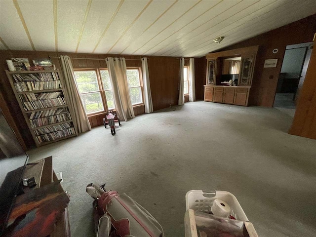 unfurnished living room with light carpet, wood walls, and vaulted ceiling
