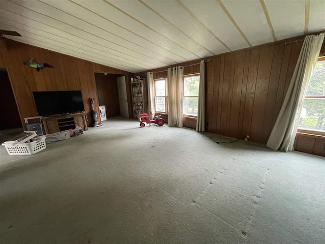 unfurnished living room featuring lofted ceiling, wood walls, and carpet floors