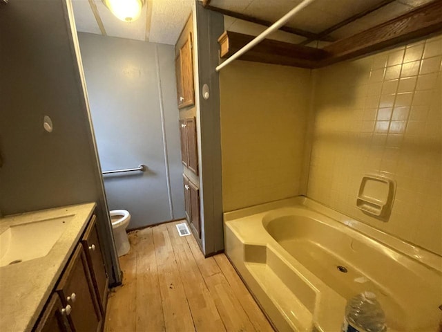 full bathroom with toilet, hardwood / wood-style floors, vanity, visible vents, and a bathing tub