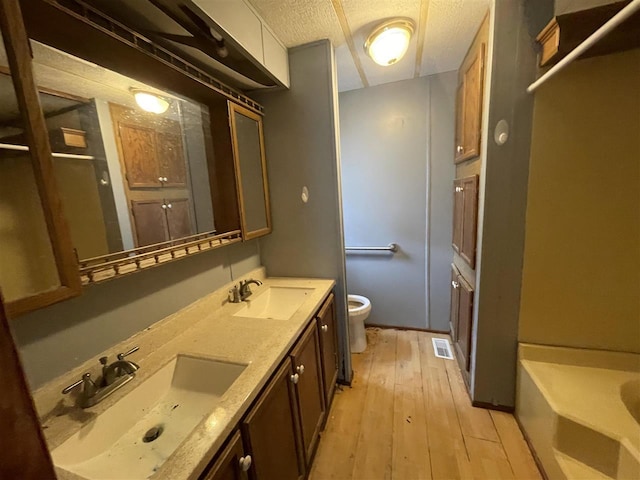 full bath featuring a sink, toilet, wood-type flooring, and visible vents