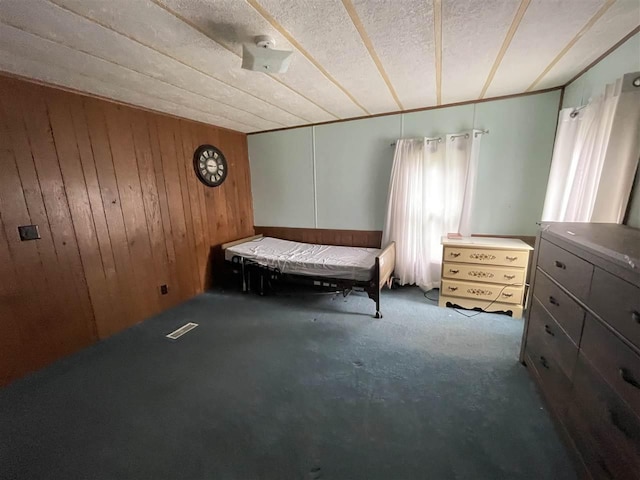 bedroom featuring wooden walls and carpet floors