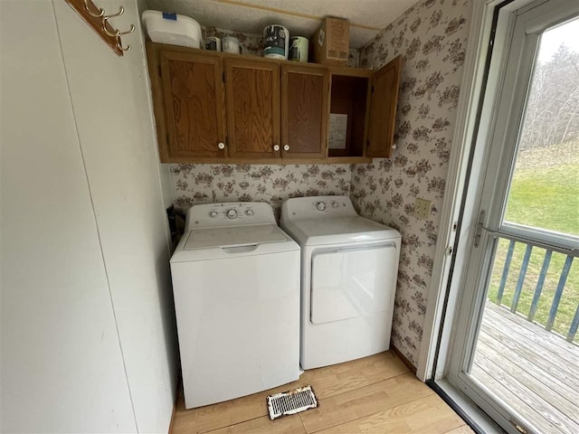 clothes washing area featuring cabinet space, visible vents, washing machine and clothes dryer, light wood finished floors, and wallpapered walls