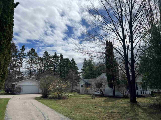 obstructed view of property featuring a garage, an outdoor structure, and a front lawn