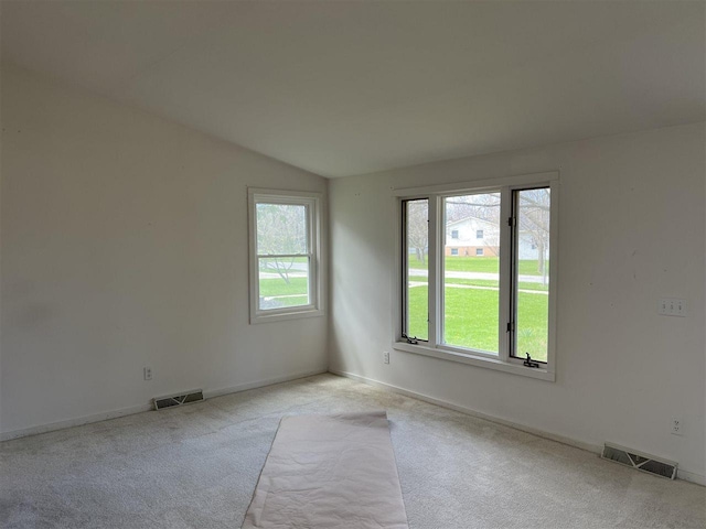empty room featuring plenty of natural light, light colored carpet, lofted ceiling, and baseboards